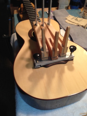 Bridge being attached with hide glue on parlor guitar by © Jay Rosenblatt
