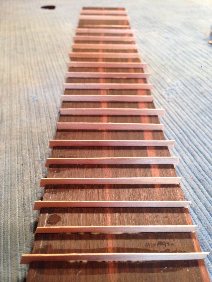 The fingerboard position markers are strips of maple inserted into the fret slots then sanded level